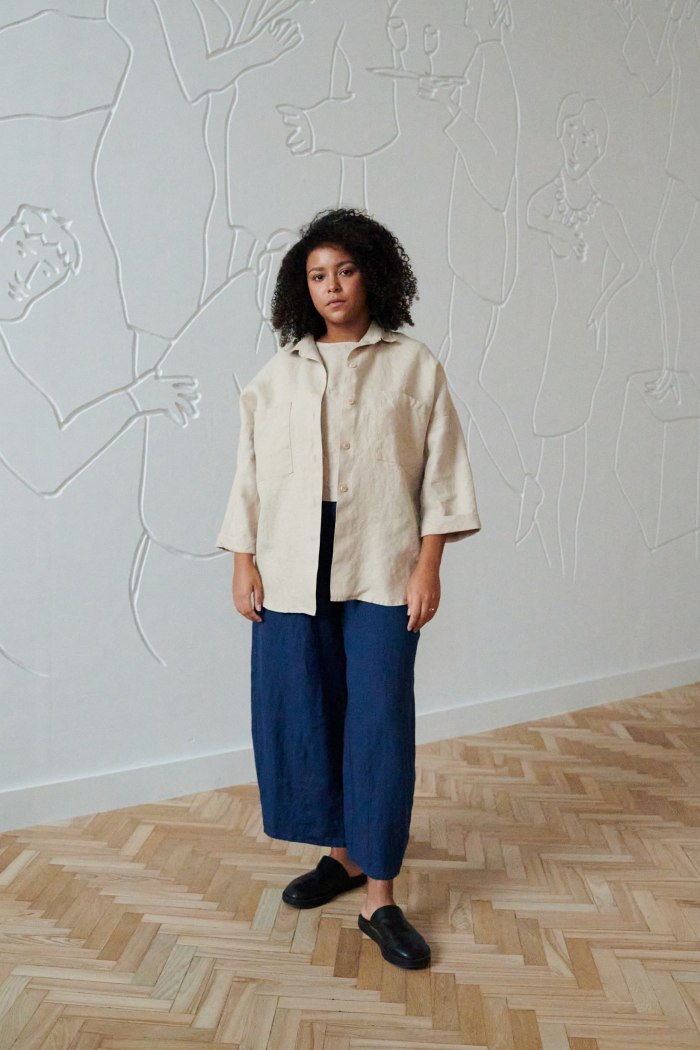 Front of a model in a beige loose-fitting shirt and relaxed fit linen trousers