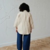 Back of a model in an oversized linen shirt with.a curved hem
