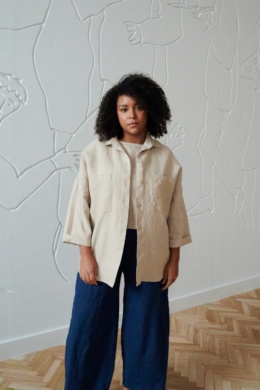 An oversized beige linen shirt with wooden buttons and three-quarter rolled up sleeves