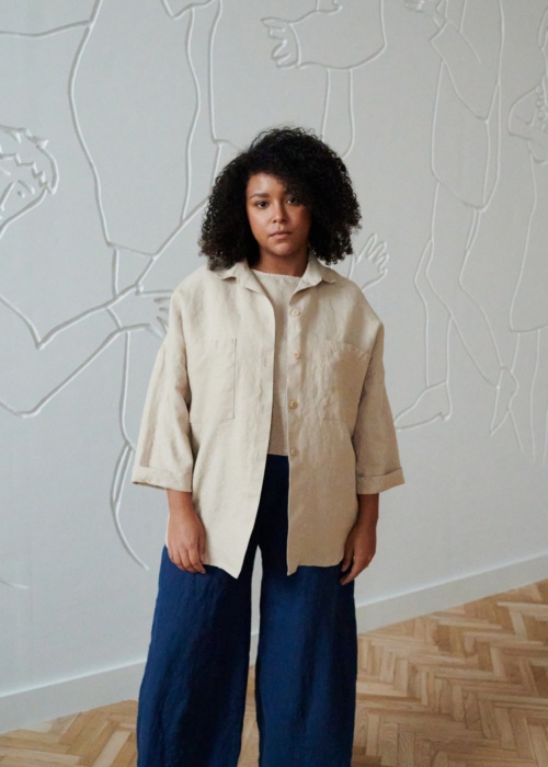 An oversized beige linen shirt with wooden buttons and three-quarter rolled up sleeves