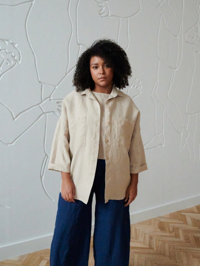 An oversized beige linen shirt with wooden buttons and three-quarter rolled up sleeves