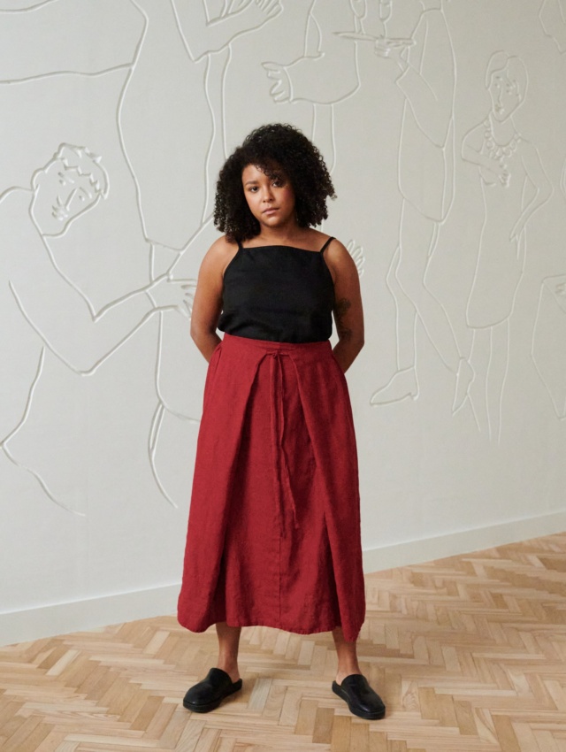 A woman wearing a long burgundy red linen skirt with thin belt and a black linen top