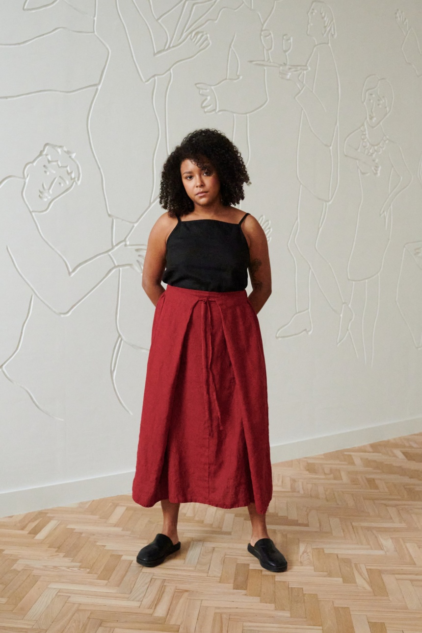 A woman wearing a long burgundy red linen skirt with thin belt and a black linen top