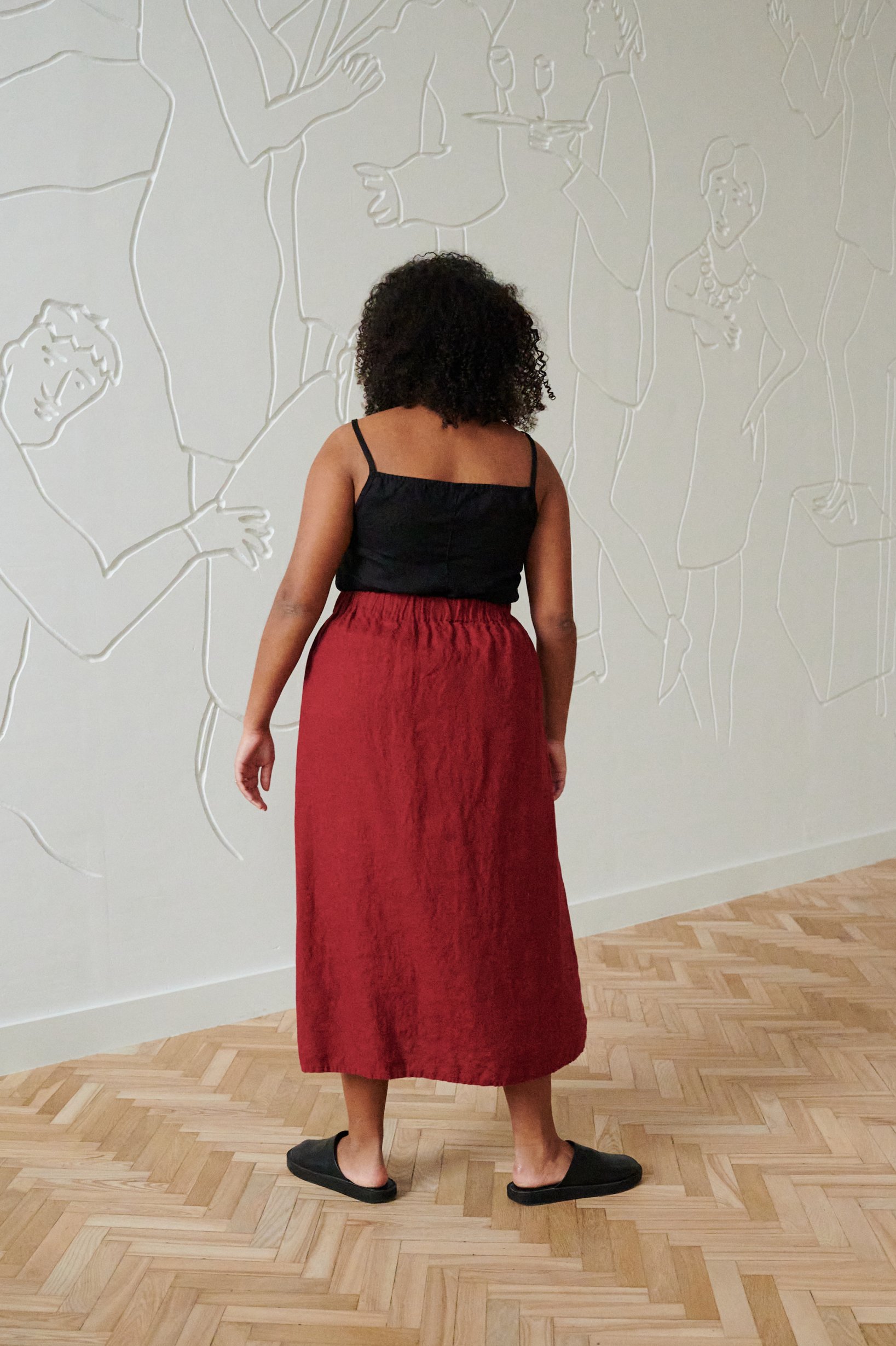 Back of a model wearing a long flowy linen skirt and a sleeveless linen top