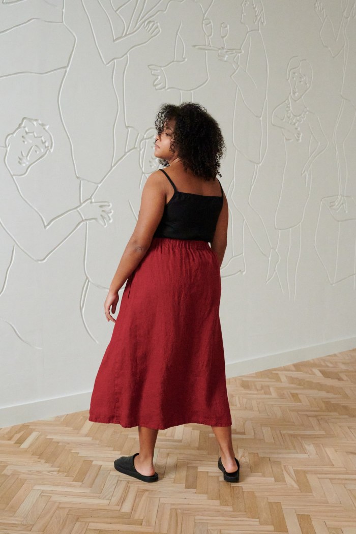 Back of a model in a long red linen skirt and a black linen spaghetti strap top