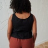 Back of a model in a casual black linen top with wide straps
