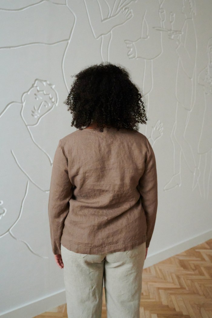 Back of a model in a cacao long sleeve straight cut linen blouse