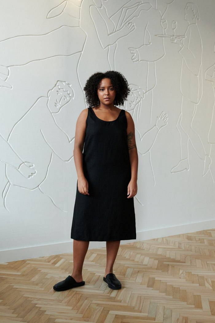 Model in a black relaxed fit sleeveless linen dress