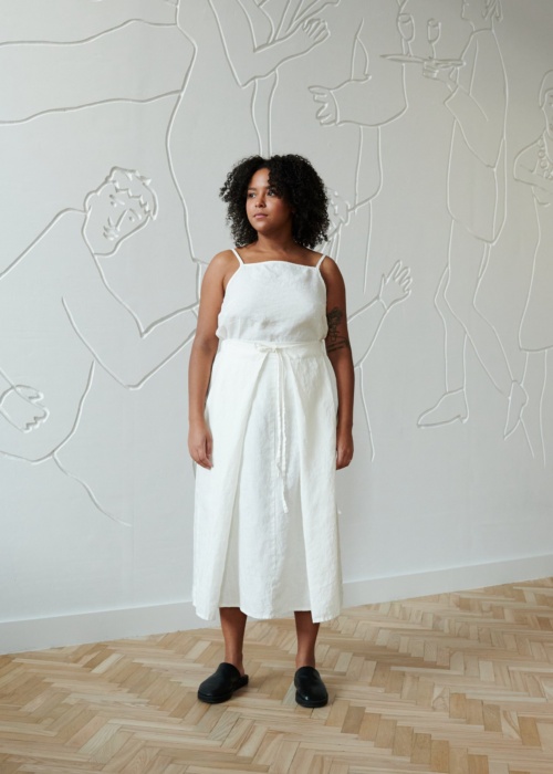 A model in a flowy linen skirt with a thin belt and a white sleeveless linen top