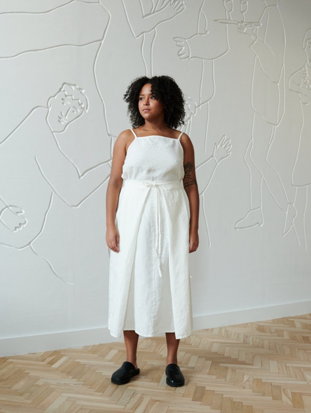 A model in a flowy linen skirt with a thin belt and a white sleeveless linen top