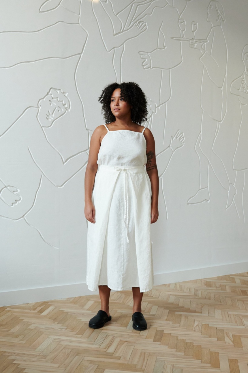 A model in a flowy linen skirt with a thin belt and a white sleeveless linen top