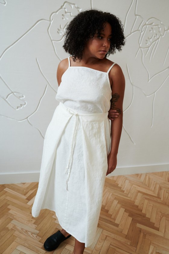 Woman wearing a milky white linen skirt and a linen top with thin straps