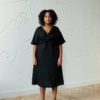 Model in a black midi linen dress with short sleeves and a V-neckline