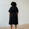 Back of a model in a black midi linen dress with short sleeves