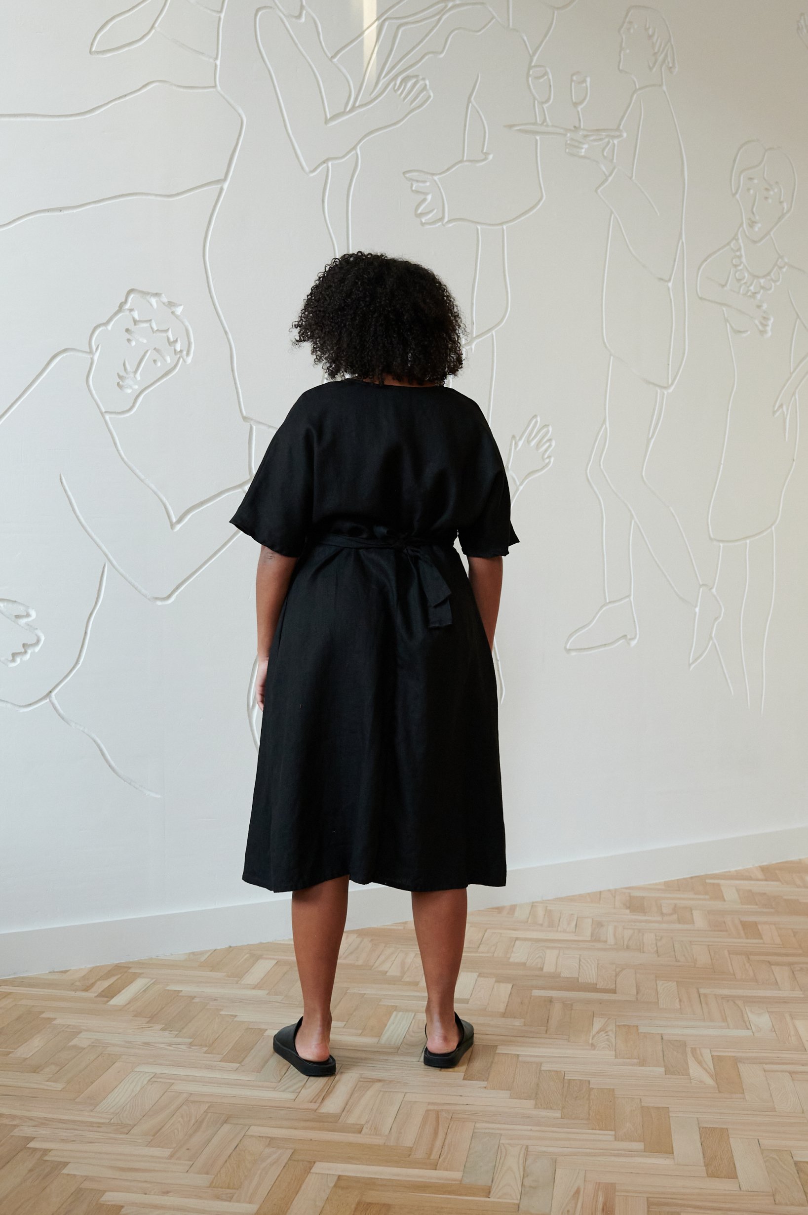 Back of a model in a black midi linen dress with short sleeves