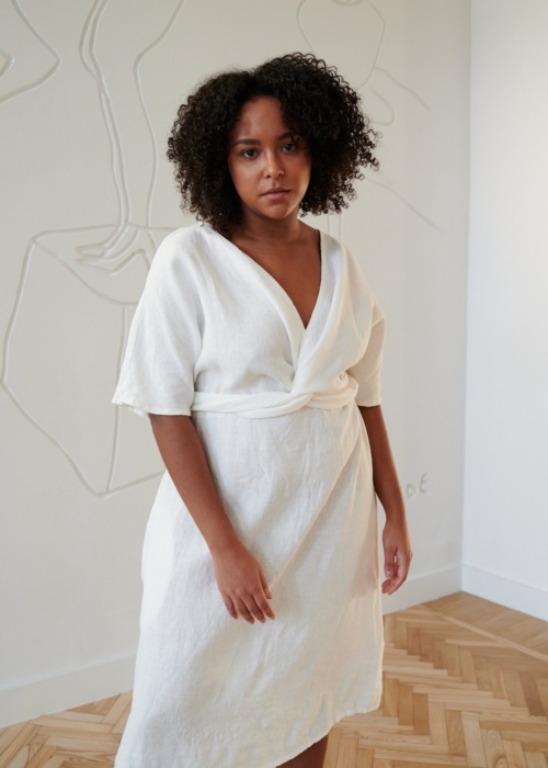 Model in a while linen dress with a V-neckline and a twist in the front