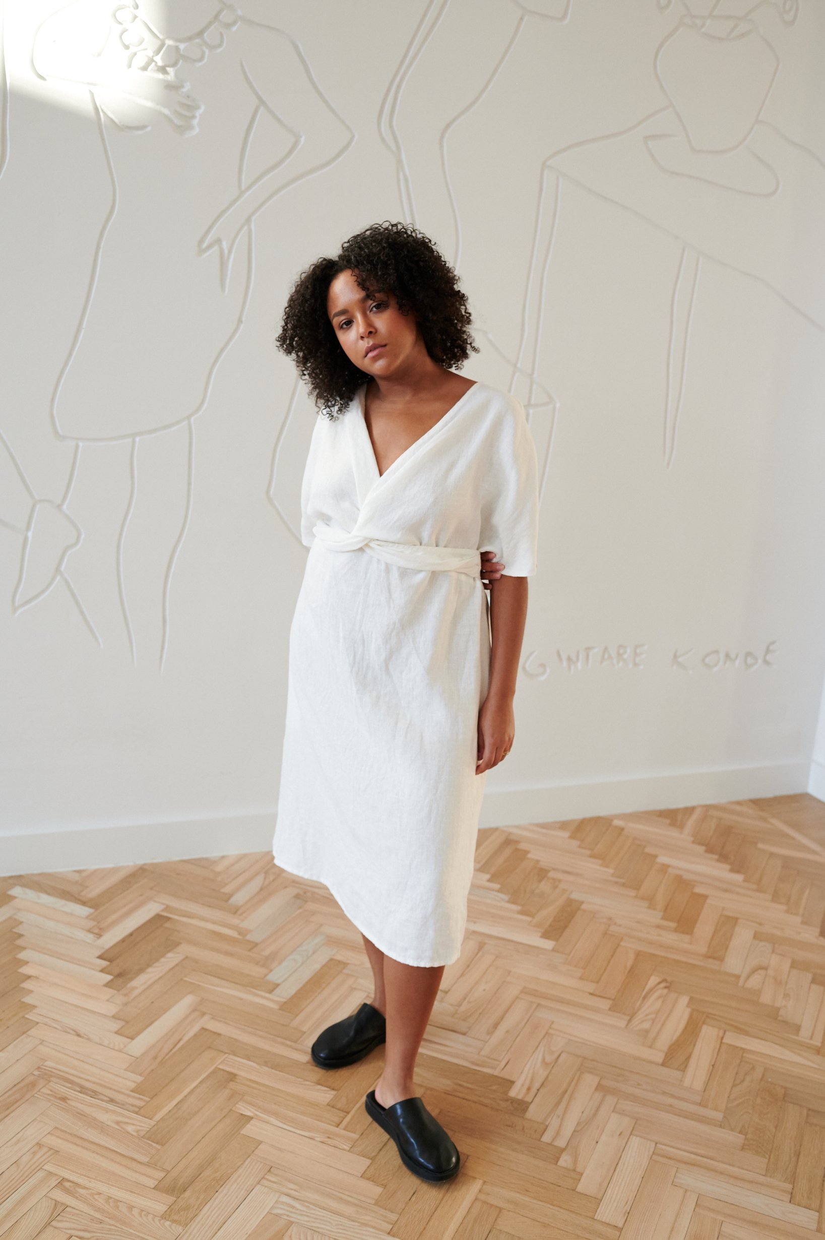 Model in a white midi linen dress with a twist in the front