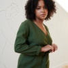 Model in a green linen dress with a belt and long sleeves
