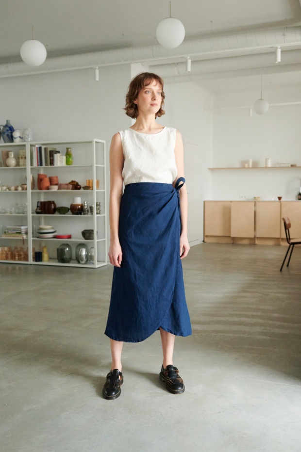 Woman wearing a white linen summer top and a blue linen wrap skirt
