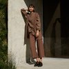 A woman wearing heavy linen wide leg trousers in cacao brown