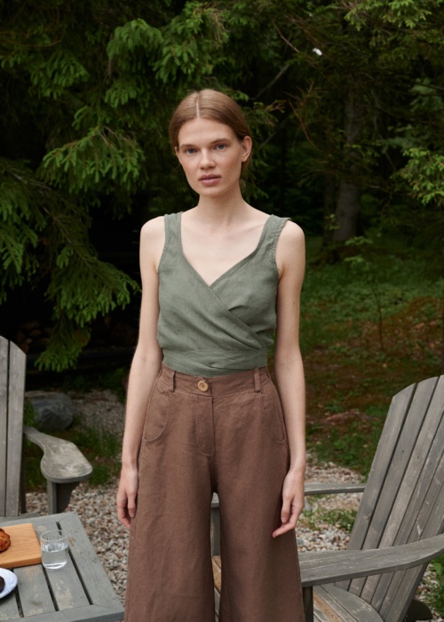 A woman wearing high waisted heavy linen trousers in brown