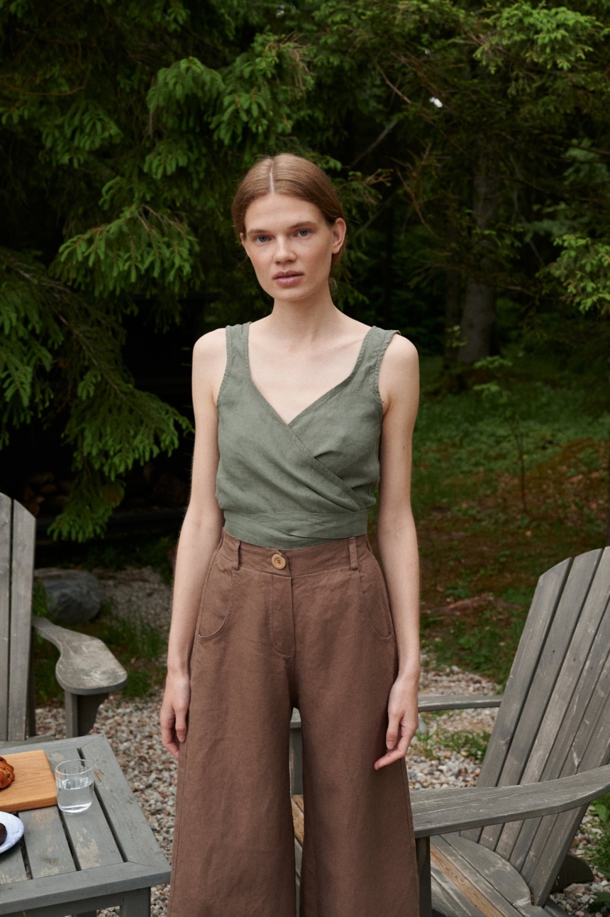 A woman wearing high waisted heavy linen trousers in brown