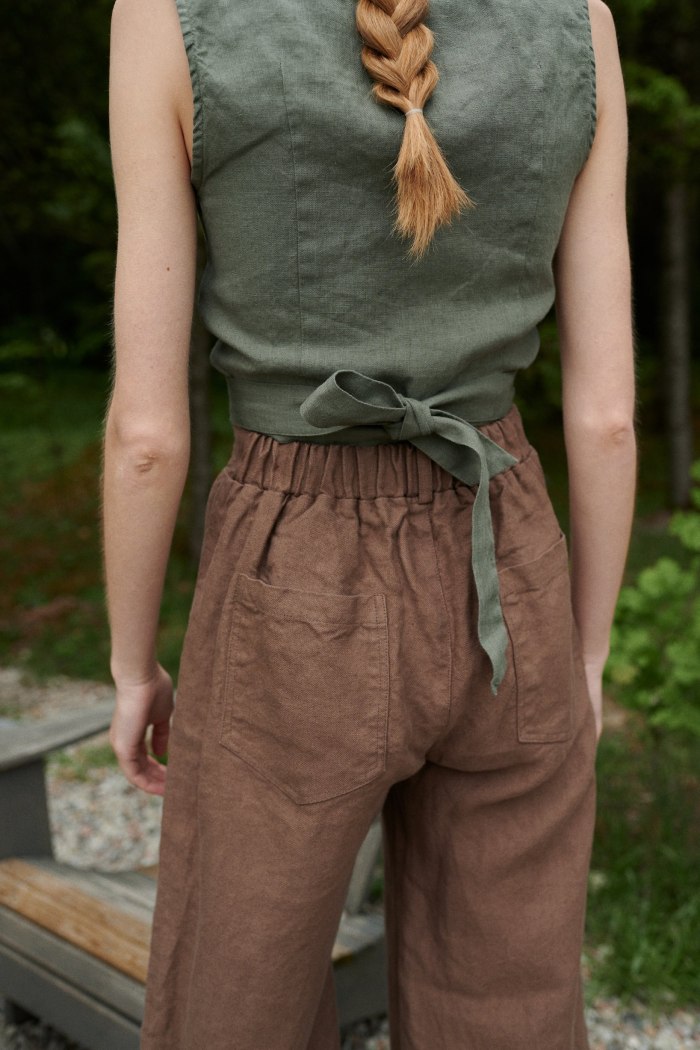 The elasticated waistband of brown heavy linen barrel leg trousers