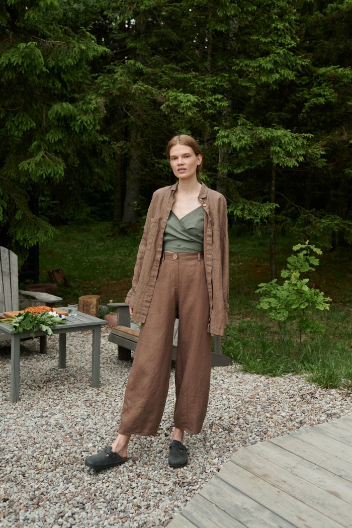 A woman standing in brown wide leg heavy linen pants