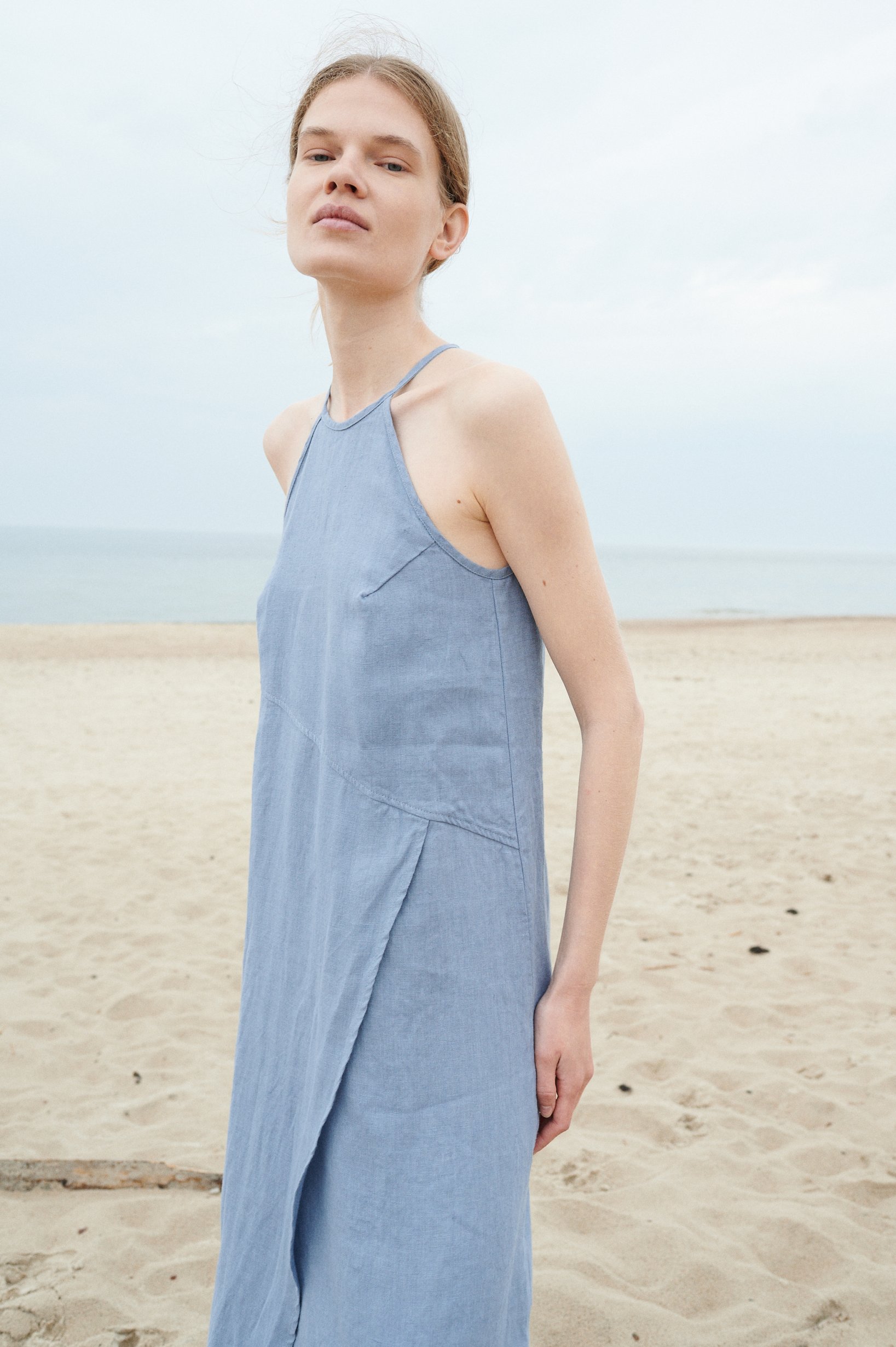 A light blue sleeveless linen dress with an an asymmetrical seam