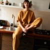 A woman sitting in barrel leg linen pants and a matching top