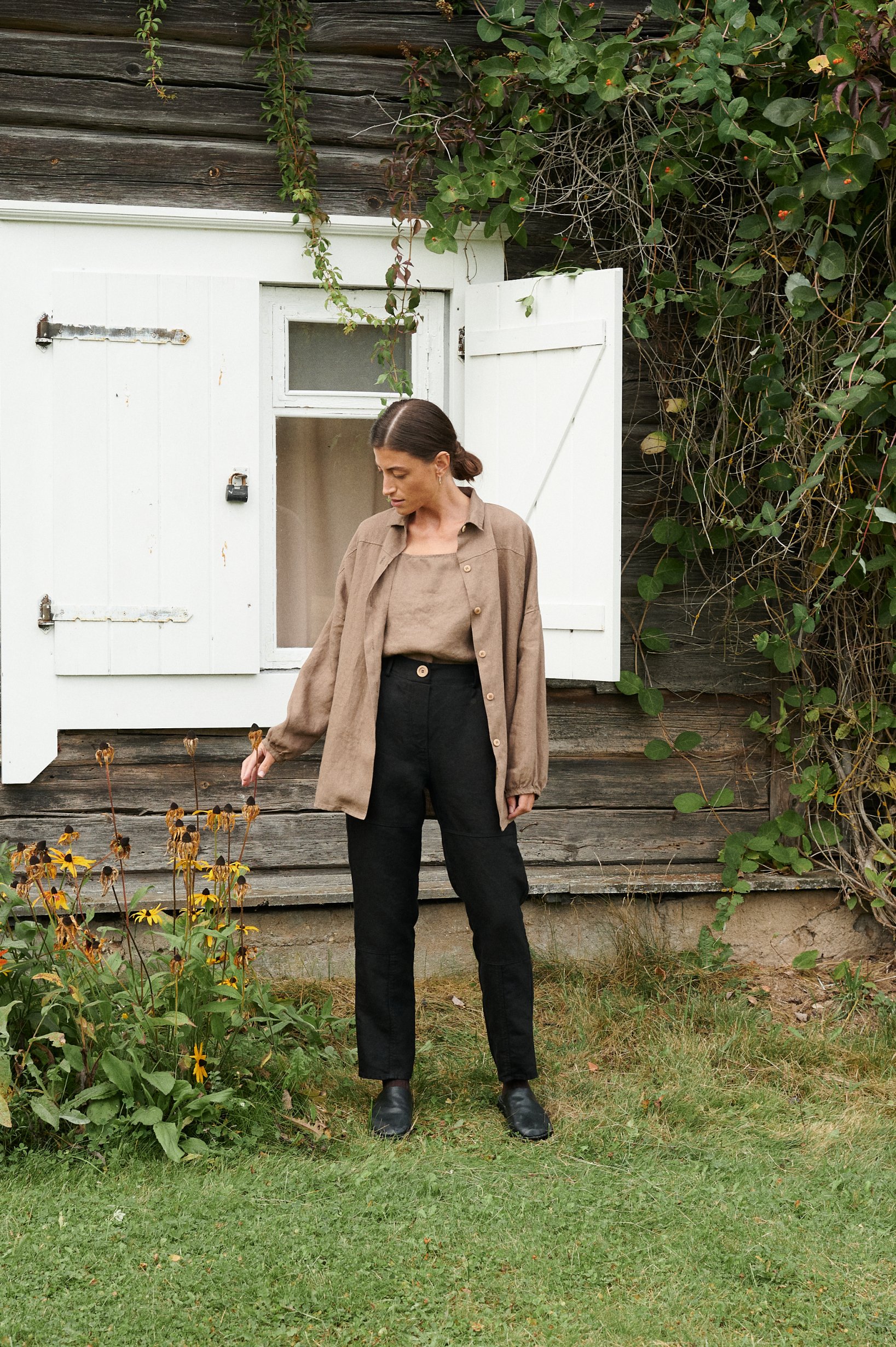 An unbuttoned loose-fitting brown linen shirt paired with black linen pants