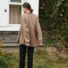 Back of a loose-fitting linen shirt with high-low curved hem and long sleeves with ruched cuffs