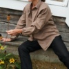 A woman sitting in loose-fitting linen brown button down