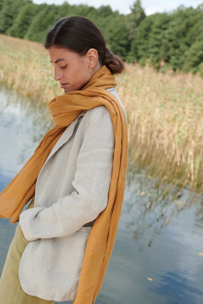 Side view of a model wearing a camel colored linen scarf around the neck