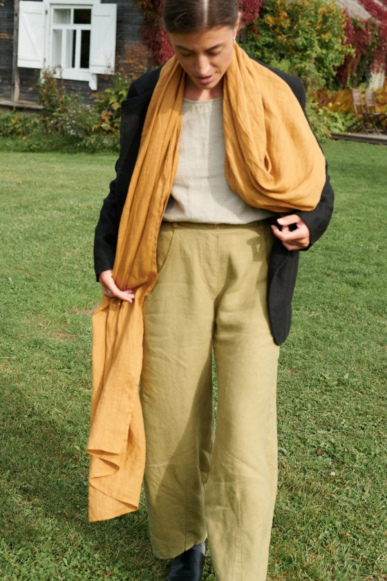 Long natural linen scarf in camel yellow color draped over shoulders