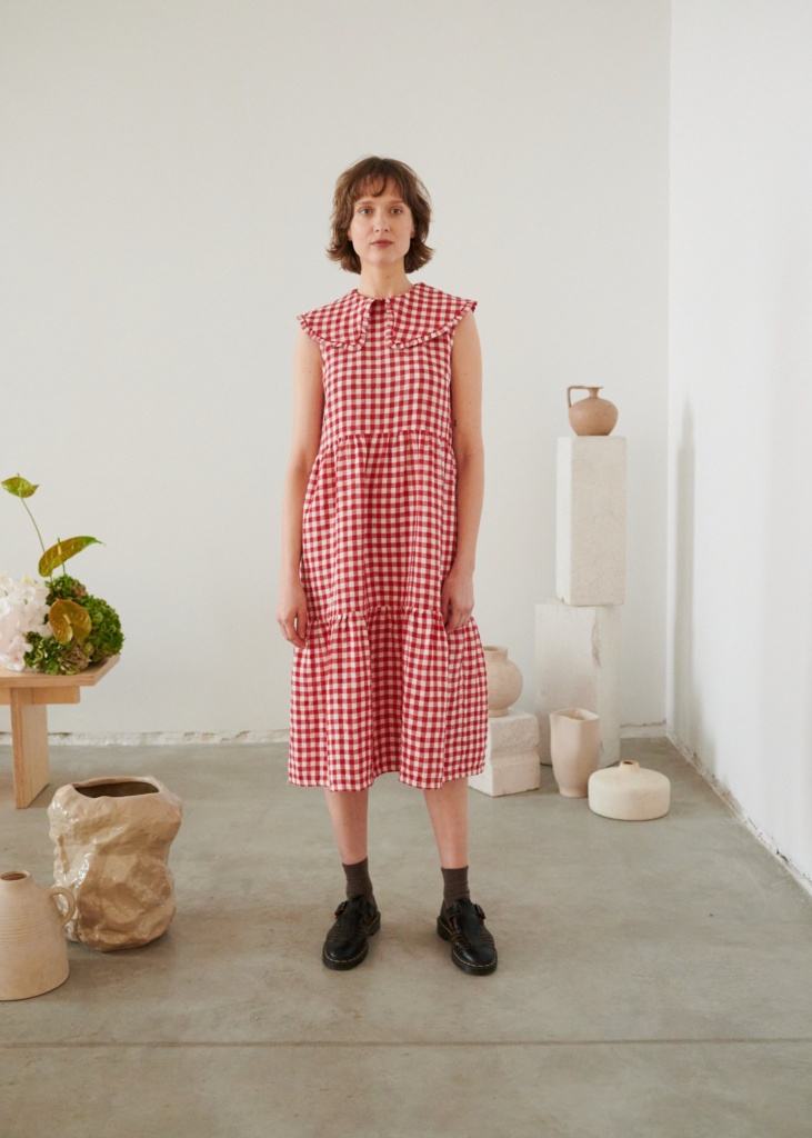 A sleeveless red gingham linen dress with an oversized frilly collar