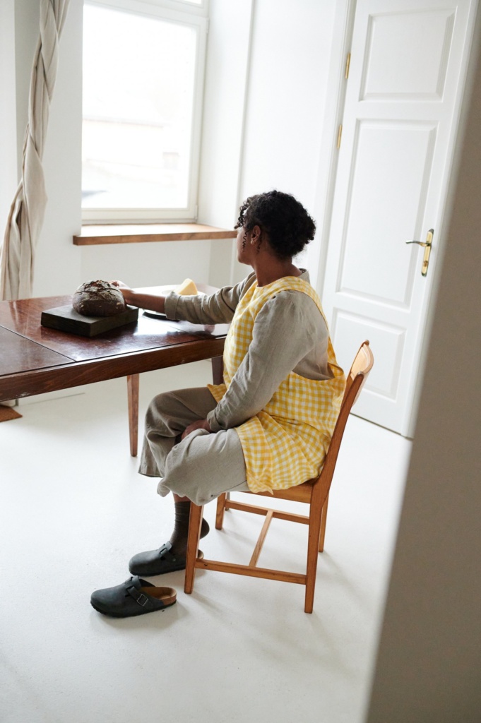 Linenfox model sitting while wearing a yellow gingham pattern apron