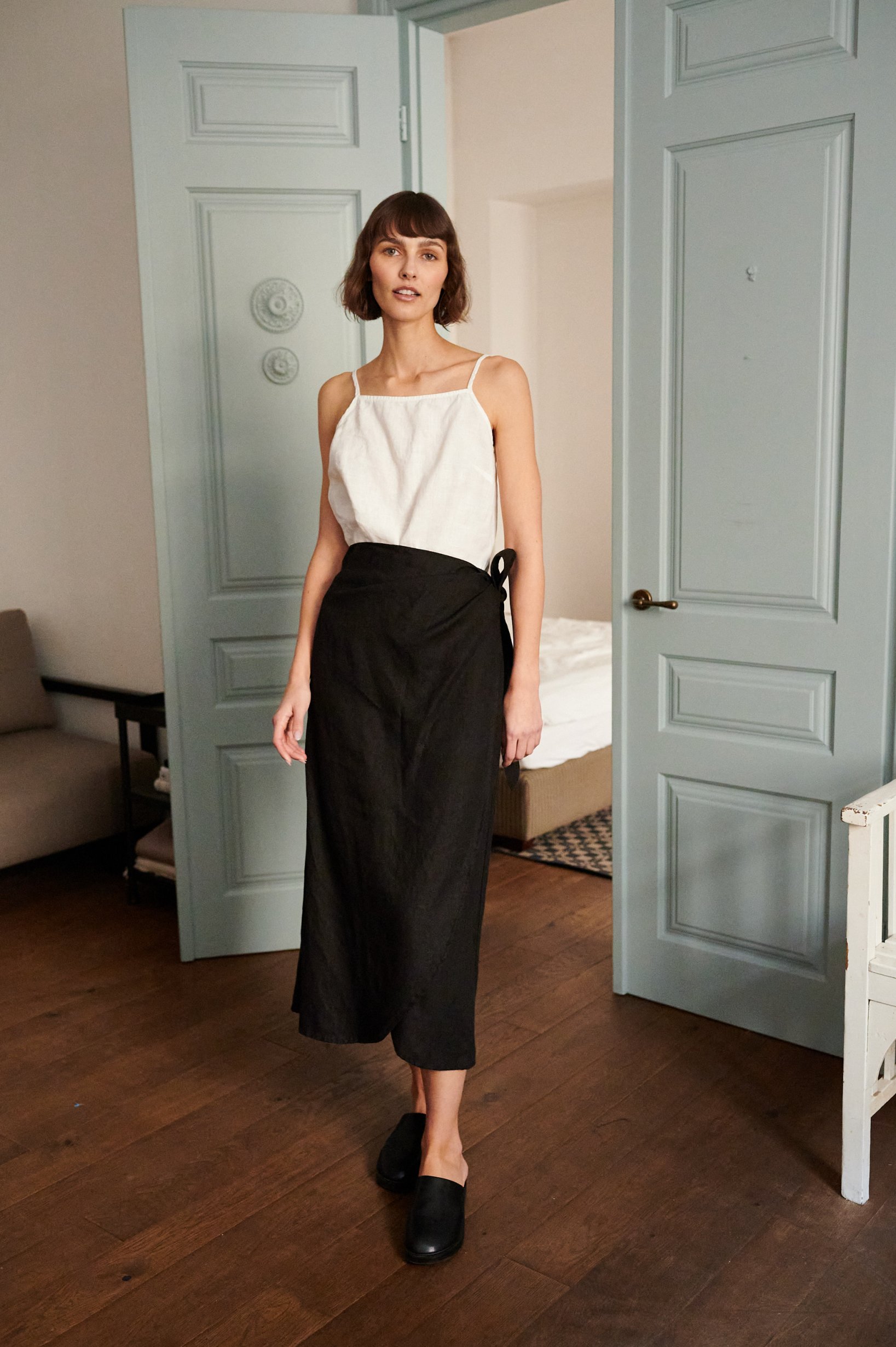 A white sleeveless linen summer top and wide-leg black linen trousers outfit