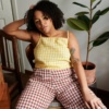 A woman sitting in brown gingham pants