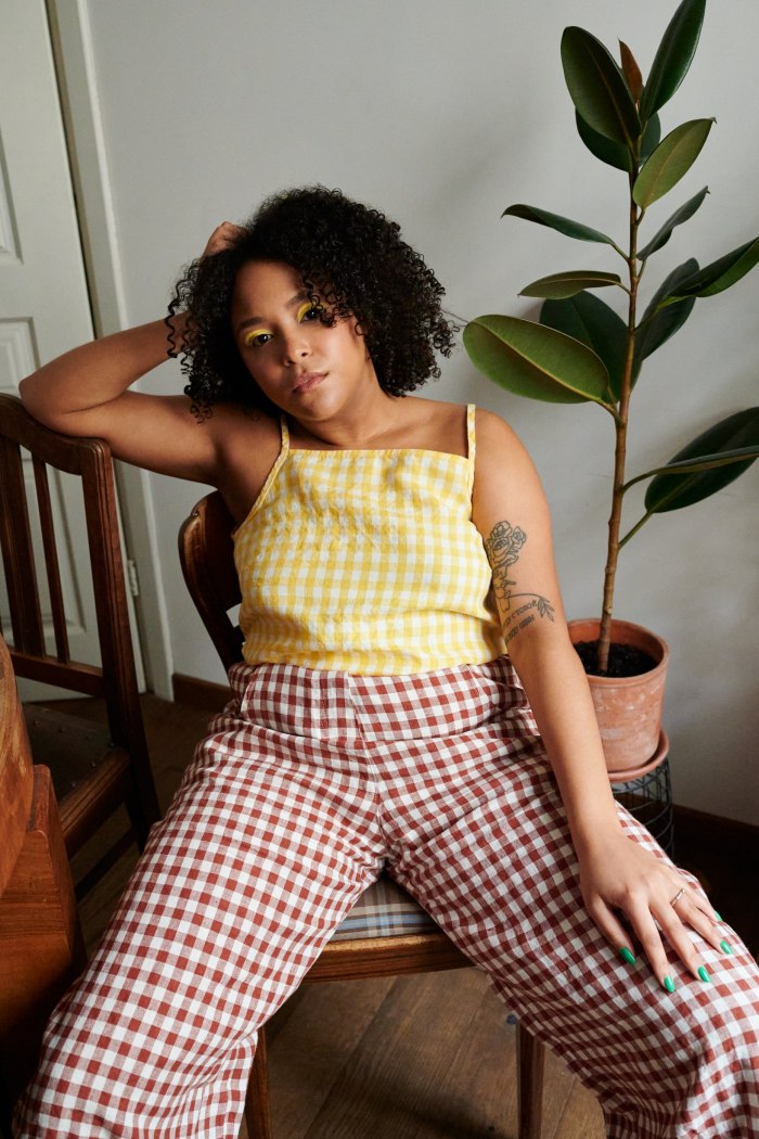 A woman sitting in brown gingham pants