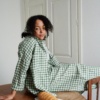 A woman sitting in oversized linen gingham shirt and matching trousers