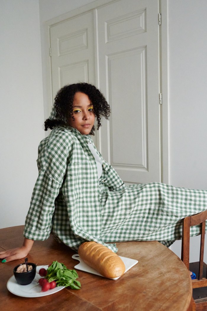 A woman sitting in oversized linen gingham shirt and matching trousers