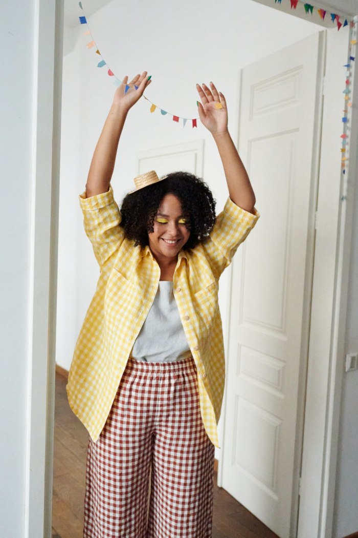 A woman in oversized line button down shirt in yellow gingham