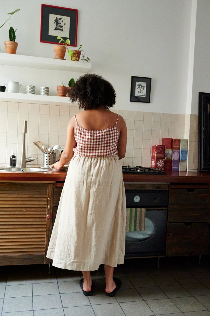 Back of a woman wearing a long A-line linen skirt and a gingham pattern linen summer top