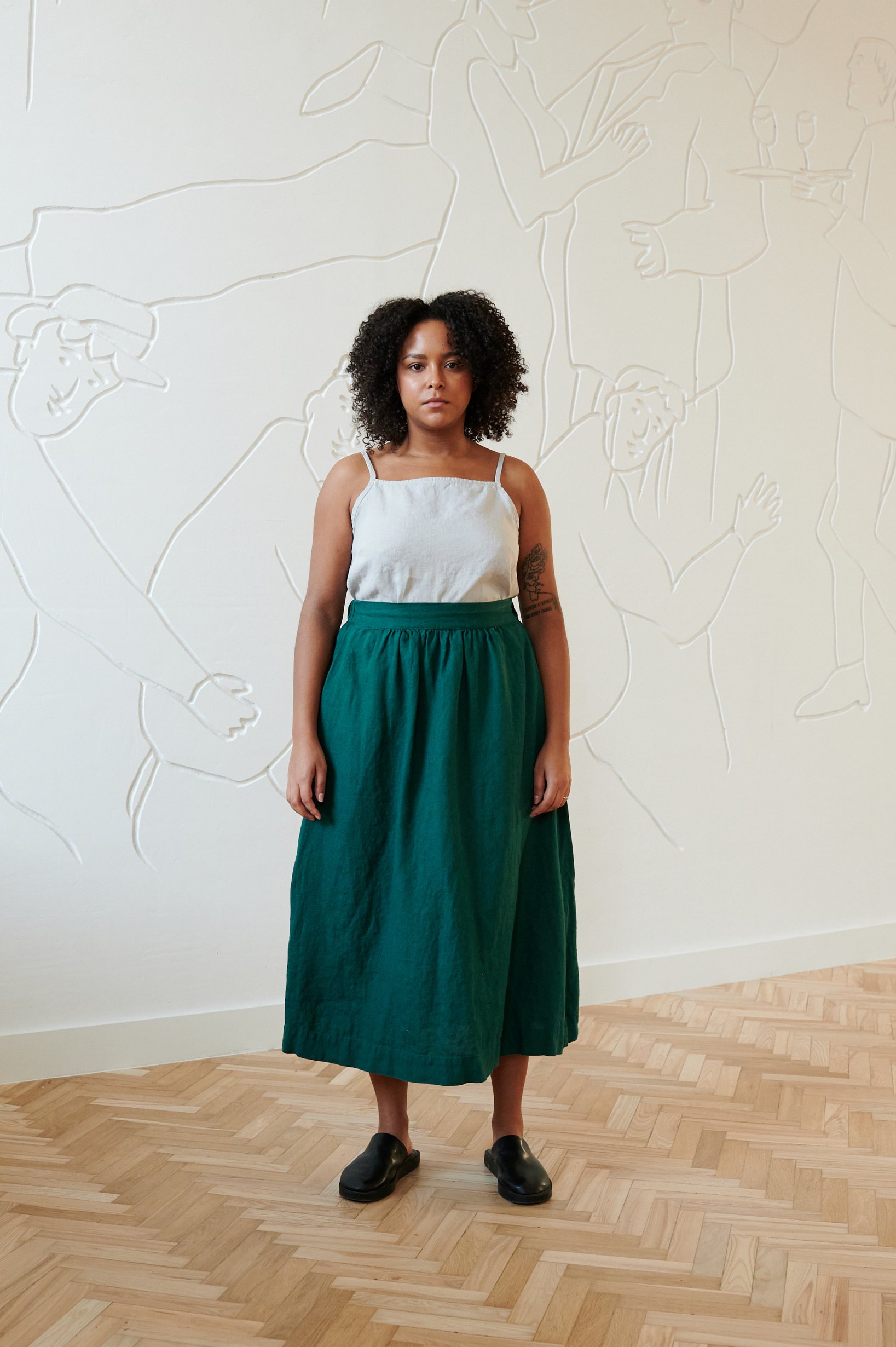Linenfox model standing in a room, in linen midi full green skirt