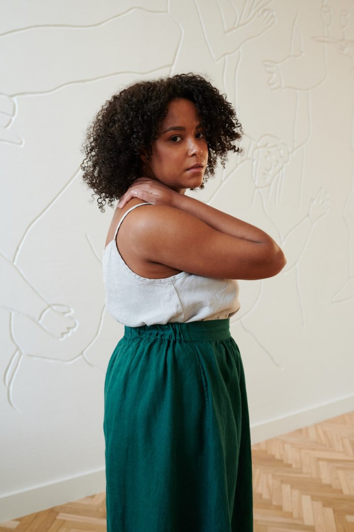 Side view of a model wearing an emerald green linen skirt with a linen top tucked in