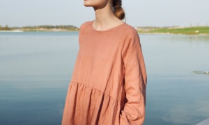 A woman wearing dark coral long sleeve linen dress