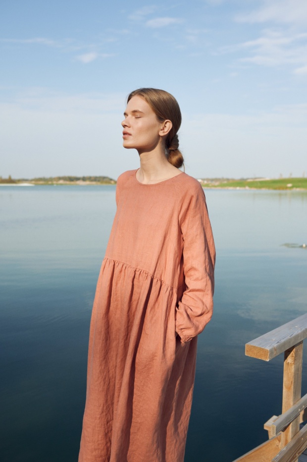 A woman wearing dark coral long sleeve linen dress