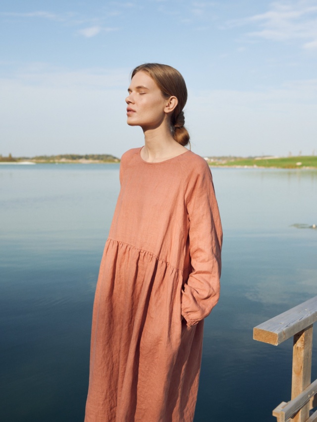 A woman wearing dark coral long sleeve linen dress