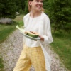 A woman walking in yellow gingham linen pants